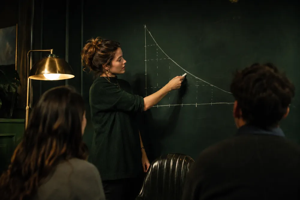 Socia de Mira explicando una curva de retención en la pizarra durante una sesión
